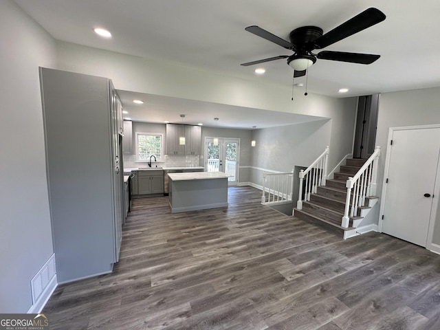 kitchen featuring sink, gray cabinets, backsplash, a kitchen island, and dark hardwood / wood-style flooring