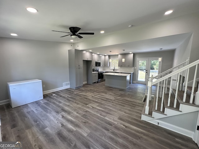 kitchen featuring stainless steel electric range oven, a kitchen island, gray cabinetry, fridge, and dark wood-type flooring