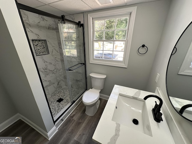 bathroom with a paneled ceiling, vanity, wood-type flooring, toilet, and walk in shower