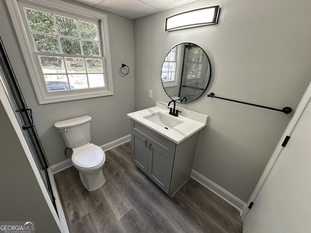 bathroom with vanity, toilet, hardwood / wood-style floors, and a drop ceiling