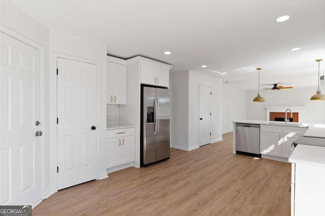 kitchen featuring appliances with stainless steel finishes, white cabinetry, light hardwood / wood-style flooring, pendant lighting, and sink