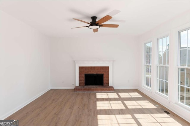 unfurnished living room with a fireplace, light wood-type flooring, and ceiling fan