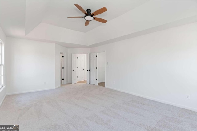 carpeted spare room with ceiling fan and a raised ceiling