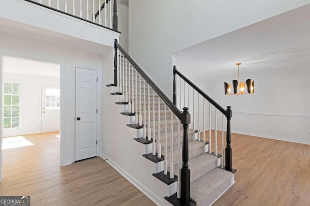 stairway featuring hardwood / wood-style flooring and an inviting chandelier