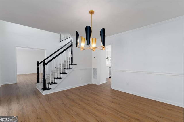 interior space featuring a notable chandelier, wood-type flooring, and ornamental molding