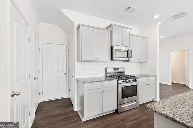 kitchen with stainless steel appliances, ornamental molding, light stone countertops, dark hardwood / wood-style flooring, and tasteful backsplash