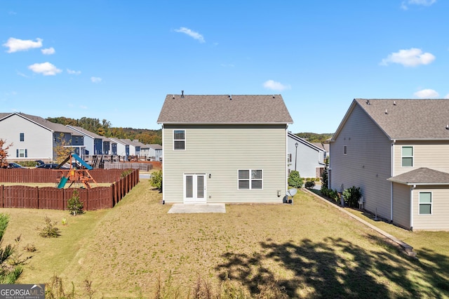 rear view of property with a yard and a playground