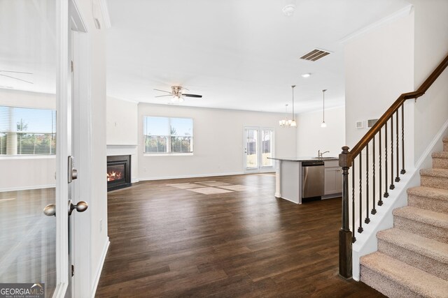 living room with dark wood-type flooring, ornamental molding, sink, and ceiling fan with notable chandelier