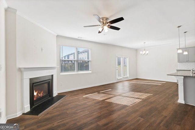 unfurnished living room with ornamental molding, dark hardwood / wood-style flooring, and ceiling fan with notable chandelier