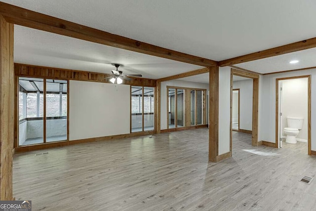 unfurnished living room with beamed ceiling, light hardwood / wood-style flooring, and ceiling fan