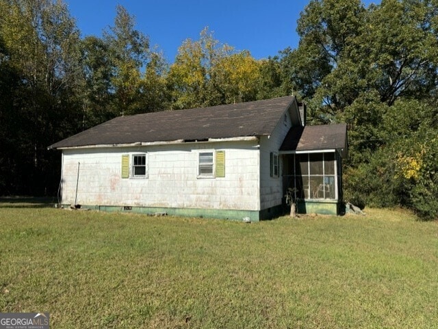 view of home's exterior featuring a lawn and a sunroom