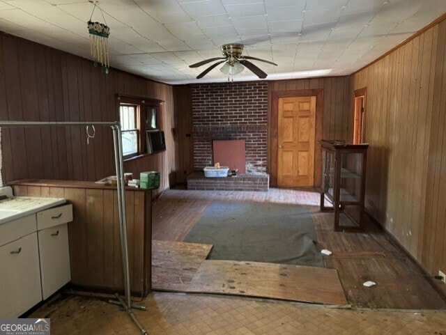 unfurnished living room with ceiling fan, wood walls, and dark hardwood / wood-style flooring