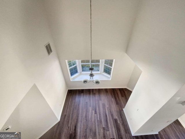 interior space featuring dark wood-type flooring and a towering ceiling