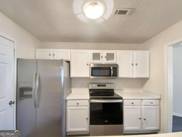 kitchen featuring appliances with stainless steel finishes, a textured ceiling, and white cabinets