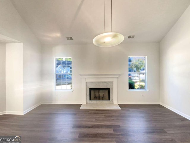 unfurnished living room featuring a high end fireplace, dark wood-type flooring, and a healthy amount of sunlight