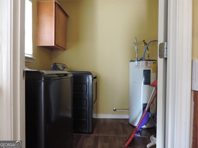 laundry room featuring electric water heater, washing machine and clothes dryer, dark hardwood / wood-style floors, and cabinets