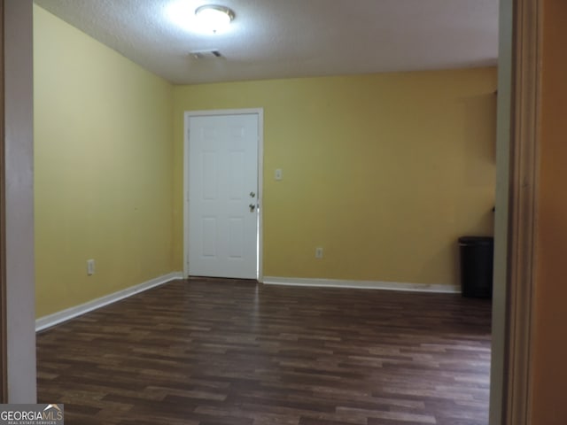 unfurnished room featuring a textured ceiling and dark hardwood / wood-style flooring