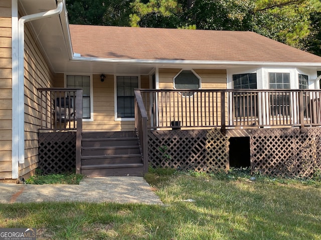 rear view of house featuring a wooden deck and a lawn