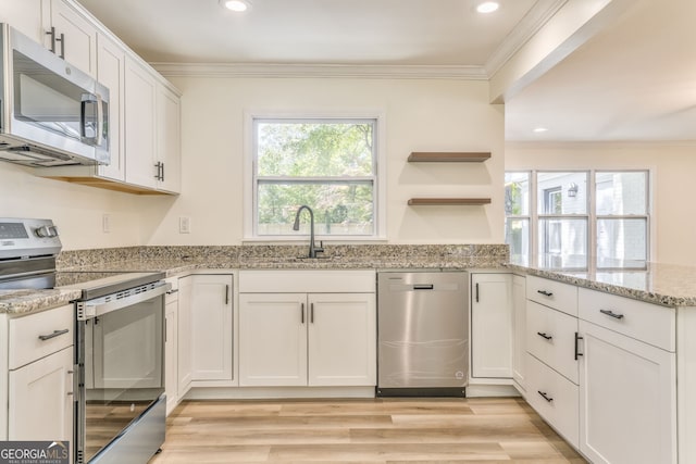 kitchen with stainless steel appliances, light stone countertops, sink, and white cabinets