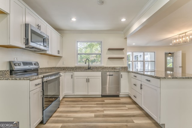 kitchen featuring appliances with stainless steel finishes, kitchen peninsula, white cabinets, and sink