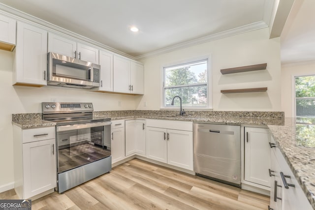 kitchen featuring appliances with stainless steel finishes, white cabinets, sink, and light hardwood / wood-style floors