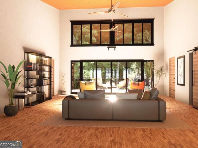 living room with a high ceiling, light hardwood / wood-style flooring, and ceiling fan