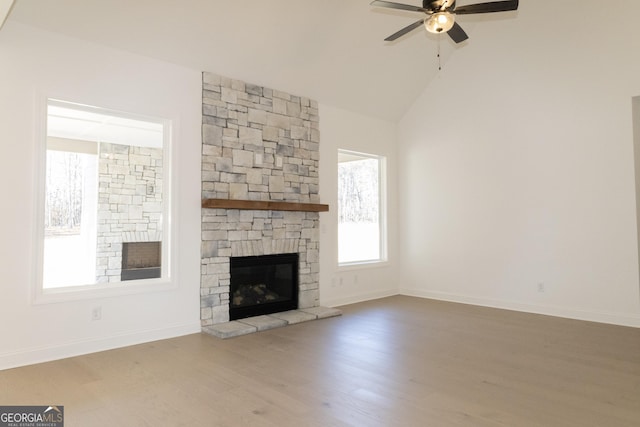 unfurnished living room featuring wood-type flooring, vaulted ceiling, a stone fireplace, and ceiling fan