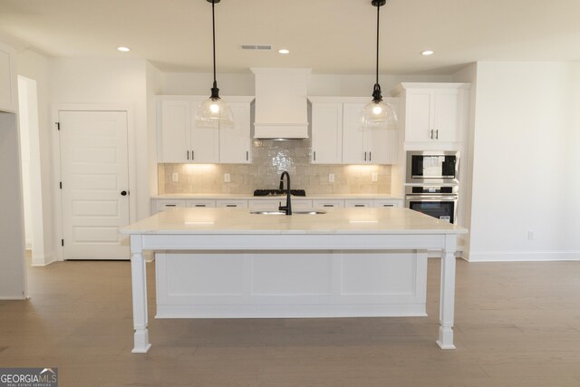 kitchen featuring sink, custom range hood, stainless steel appliances, and hanging light fixtures