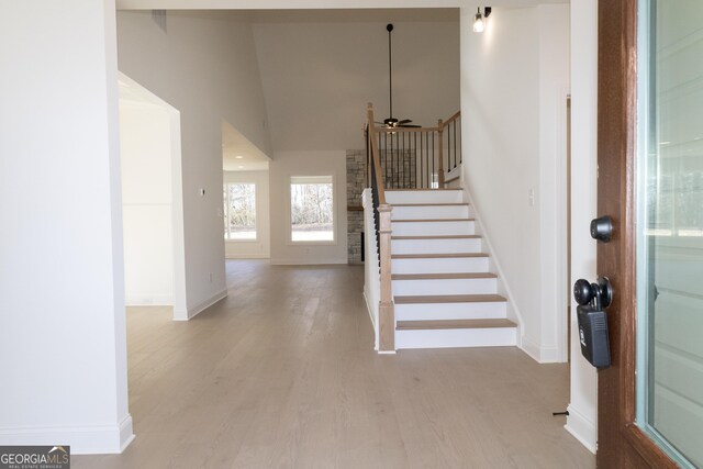 foyer entrance with ceiling fan, light hardwood / wood-style floors, and vaulted ceiling