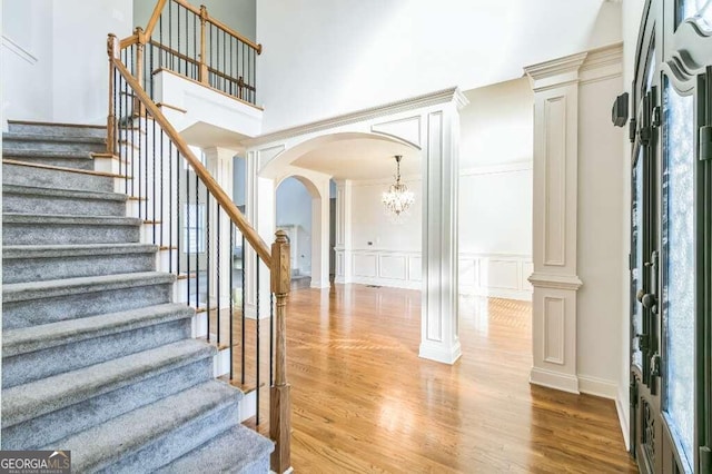 foyer with light hardwood / wood-style floors, a high ceiling, and ornate columns