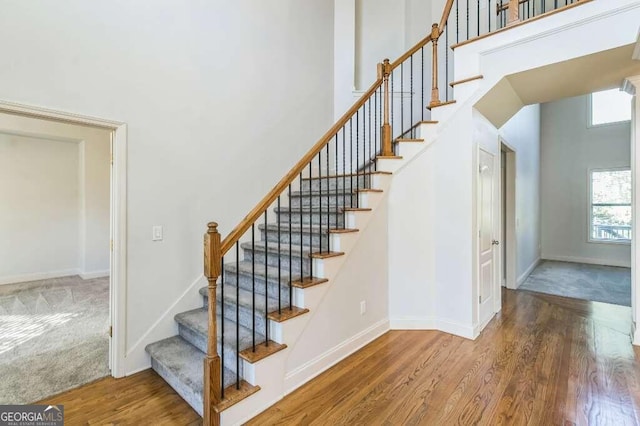 stairs with a towering ceiling and hardwood / wood-style floors