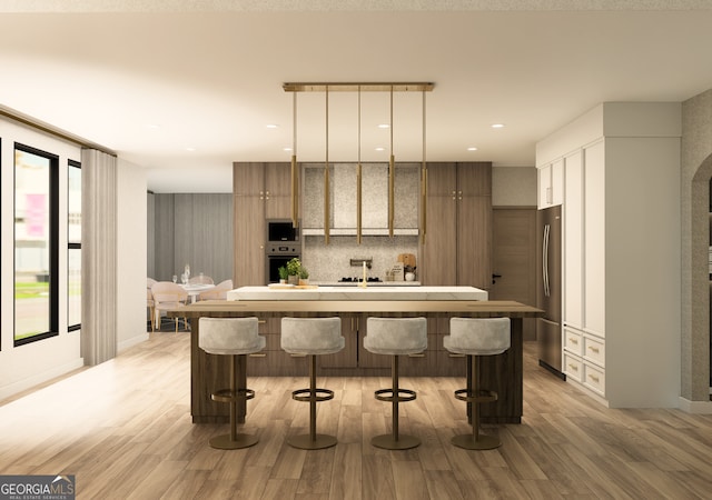 kitchen with a kitchen breakfast bar, appliances with stainless steel finishes, pendant lighting, and light hardwood / wood-style floors