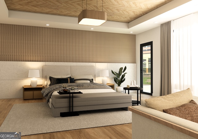 bedroom featuring a tray ceiling, light hardwood / wood-style floors, and access to outside