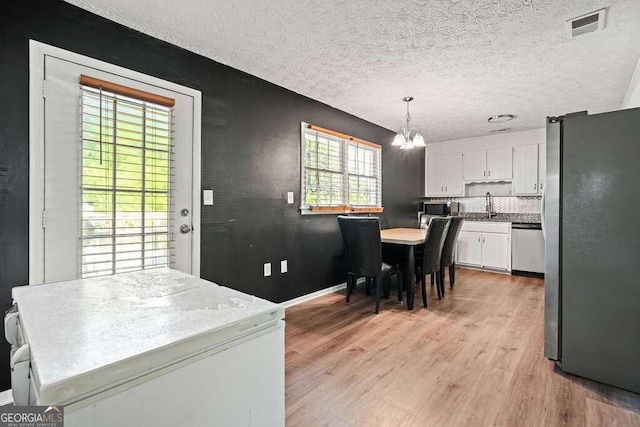 dining space featuring light hardwood / wood-style floors, a textured ceiling, a wealth of natural light, and a chandelier