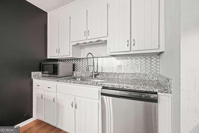 kitchen with decorative backsplash, sink, white cabinetry, appliances with stainless steel finishes, and light hardwood / wood-style floors