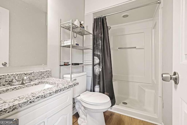 bathroom featuring vanity, wood-type flooring, toilet, and walk in shower