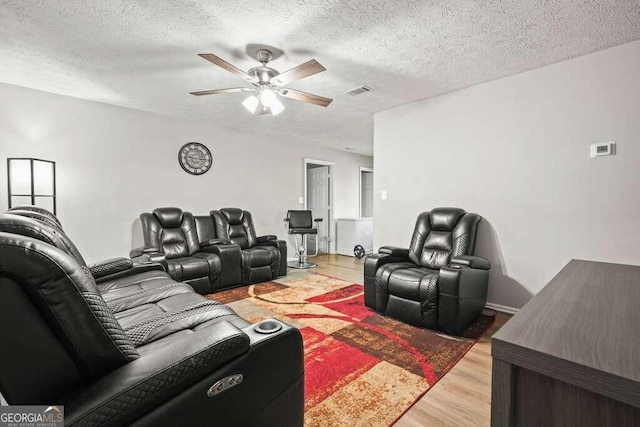 living room with ceiling fan, a textured ceiling, and hardwood / wood-style floors