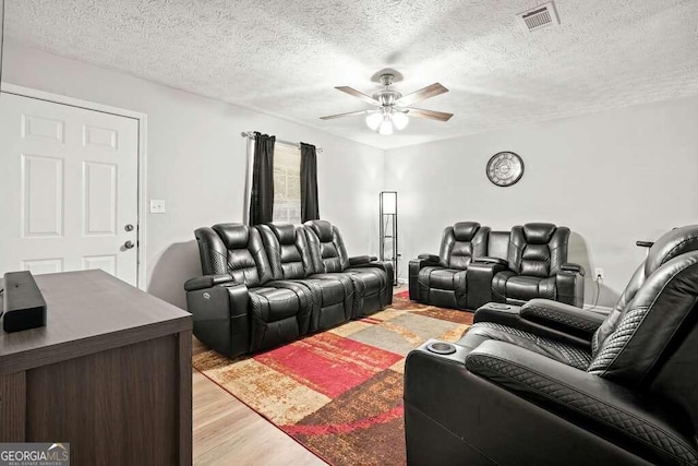 living room featuring light hardwood / wood-style flooring, a textured ceiling, and ceiling fan