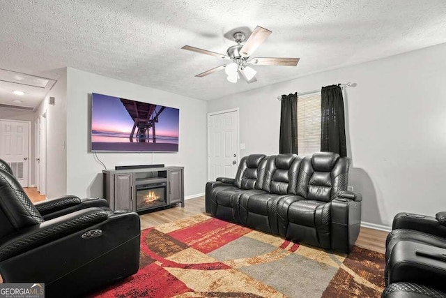 cinema featuring light hardwood / wood-style flooring, a textured ceiling, and ceiling fan