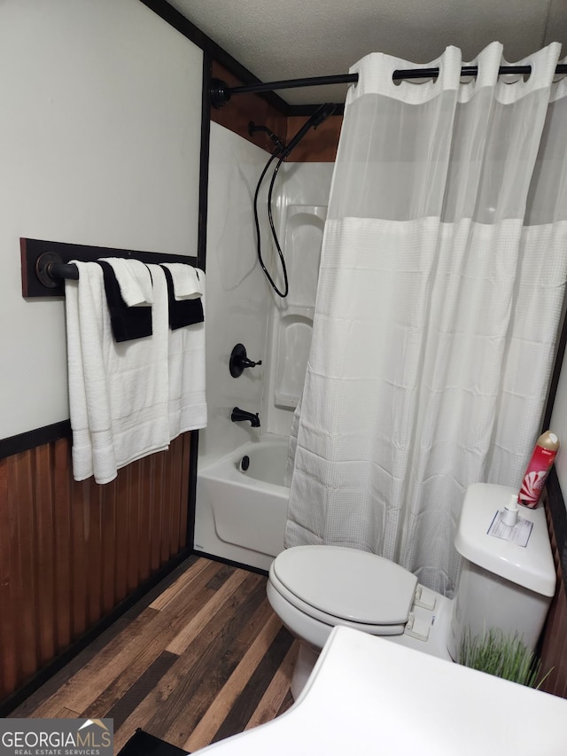 bathroom featuring hardwood / wood-style flooring, shower / tub combo with curtain, a textured ceiling, and toilet