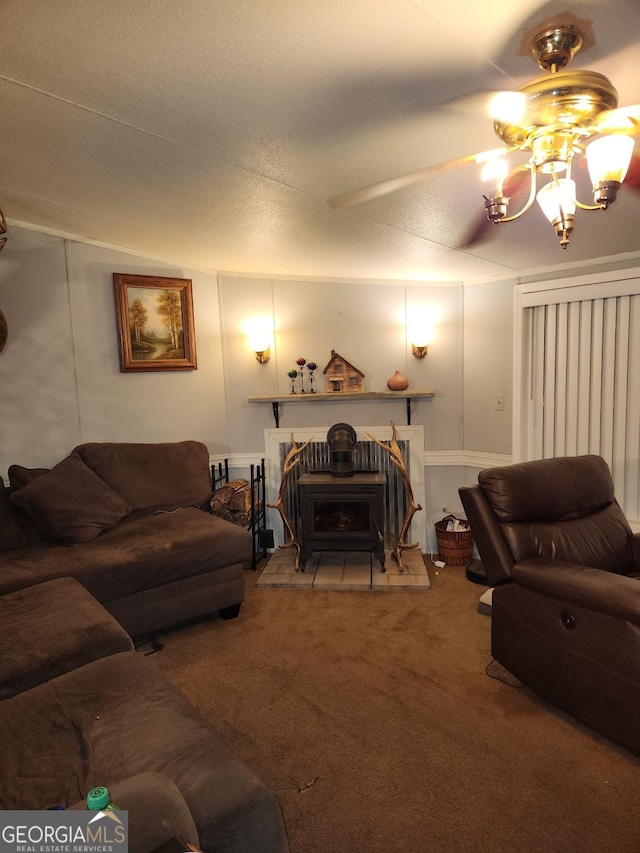 carpeted living room featuring ceiling fan with notable chandelier, a wood stove, and a textured ceiling