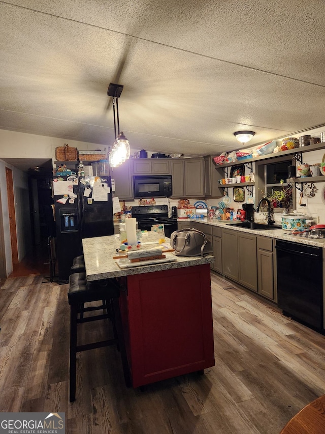 kitchen featuring pendant lighting, wood-type flooring, black appliances, and sink