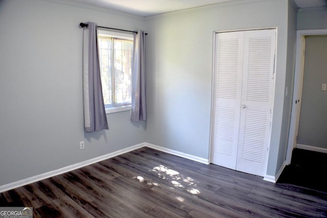 unfurnished bedroom featuring a closet, crown molding, and dark hardwood / wood-style flooring