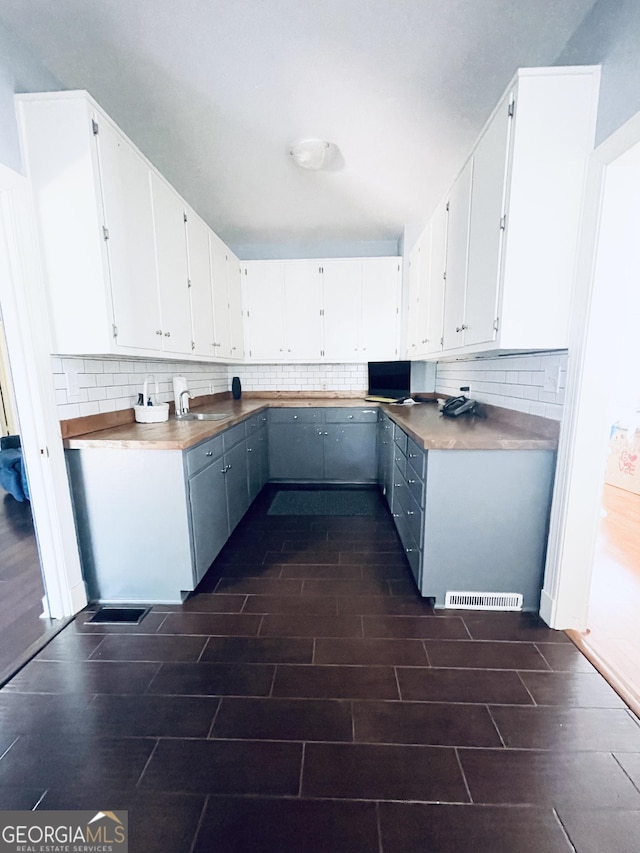 kitchen featuring butcher block counters, white cabinets, and backsplash