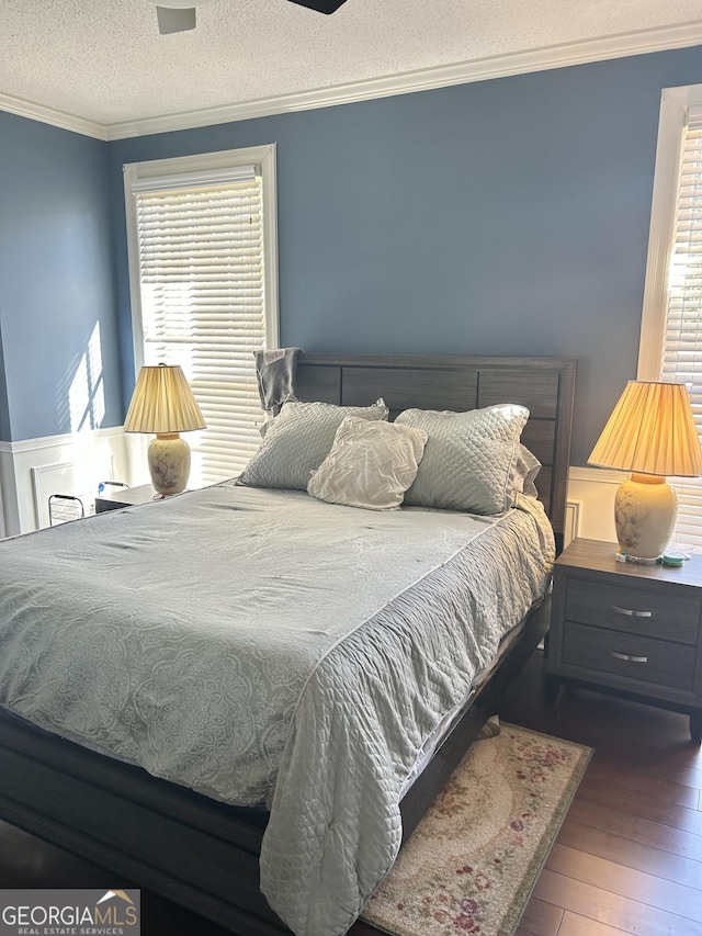 bedroom featuring ornamental molding, dark hardwood / wood-style floors, and a textured ceiling