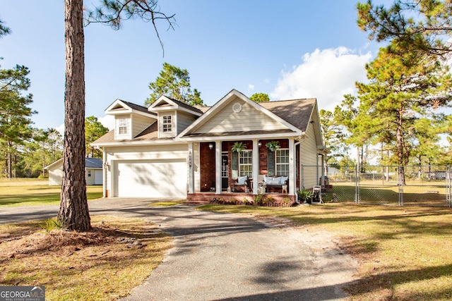 view of front of property featuring a front lawn, aphalt driveway, fence, covered porch, and an attached garage