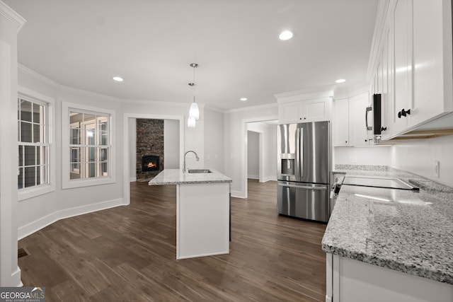 kitchen with appliances with stainless steel finishes, sink, an island with sink, decorative light fixtures, and white cabinets