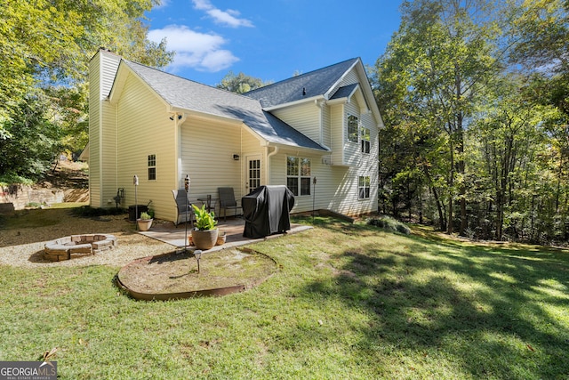 rear view of house with a yard, a patio, and a fire pit