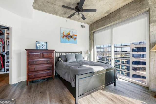 bedroom featuring hardwood / wood-style floors, a walk in closet, a closet, and ceiling fan