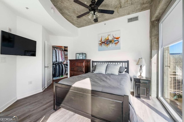 bedroom with ceiling fan, a closet, a spacious closet, and hardwood / wood-style flooring